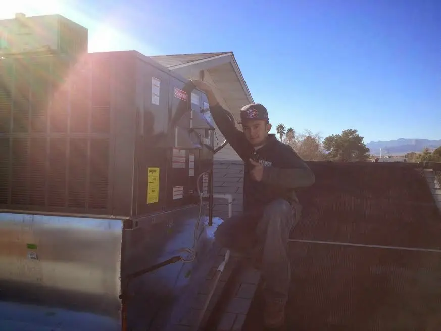 HVAC technician performing Air Duct Cleaning on a rooftop unit in Kearney