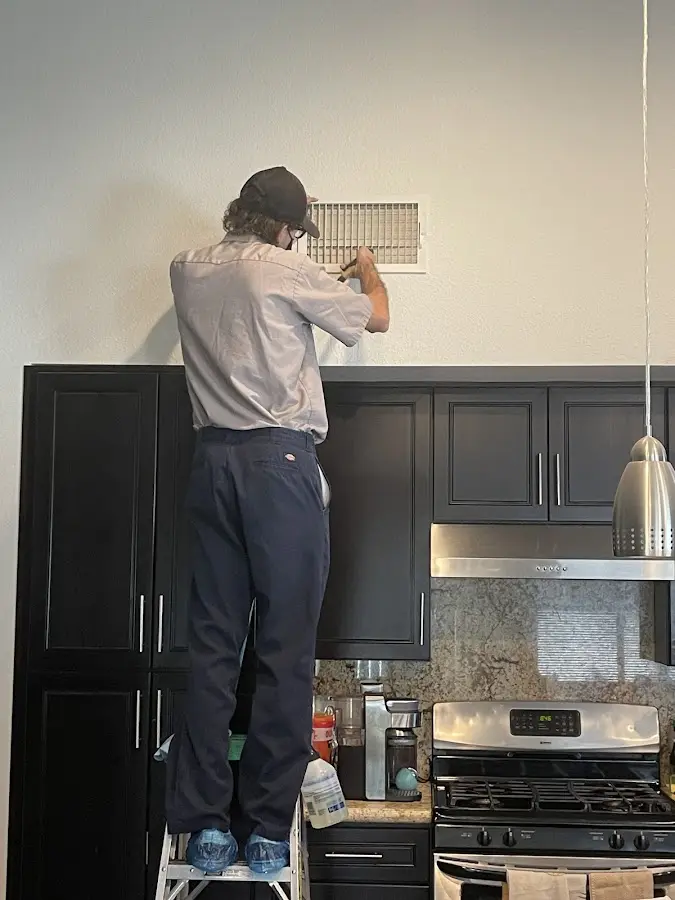 Technician inspecting an air vent during HVAC service in Kearney